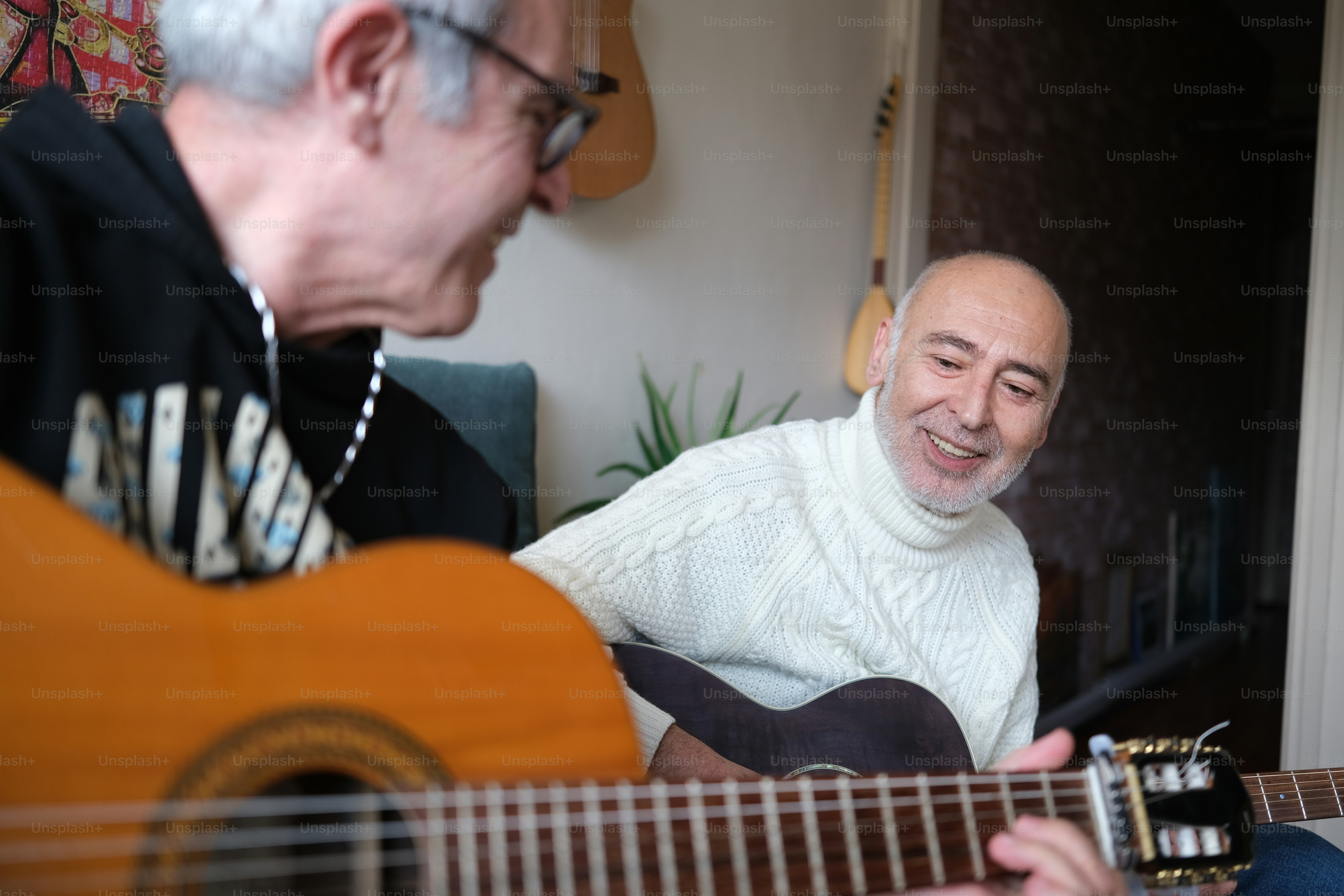 a man playing a guitar next to another man