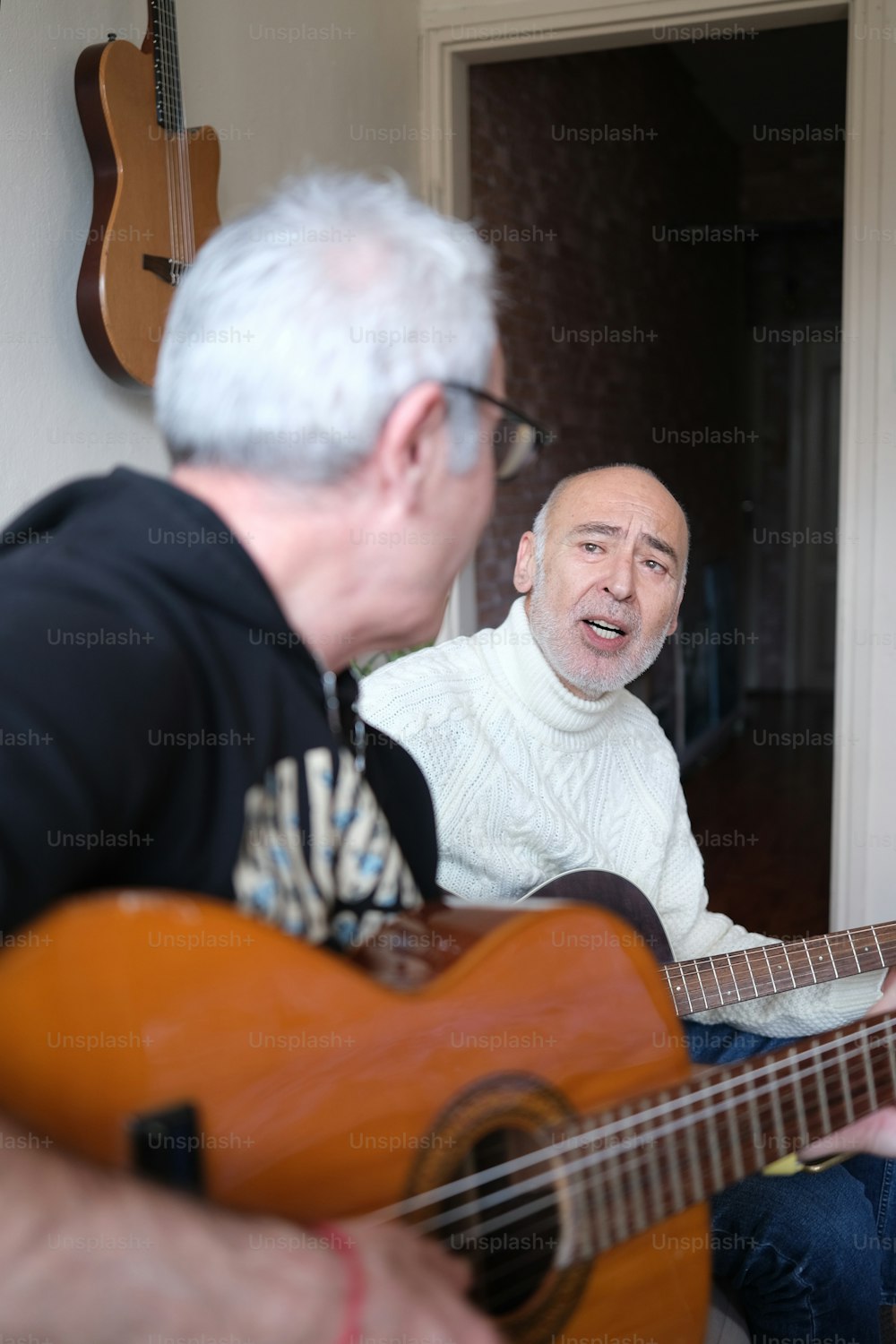 a man playing a guitar next to another man