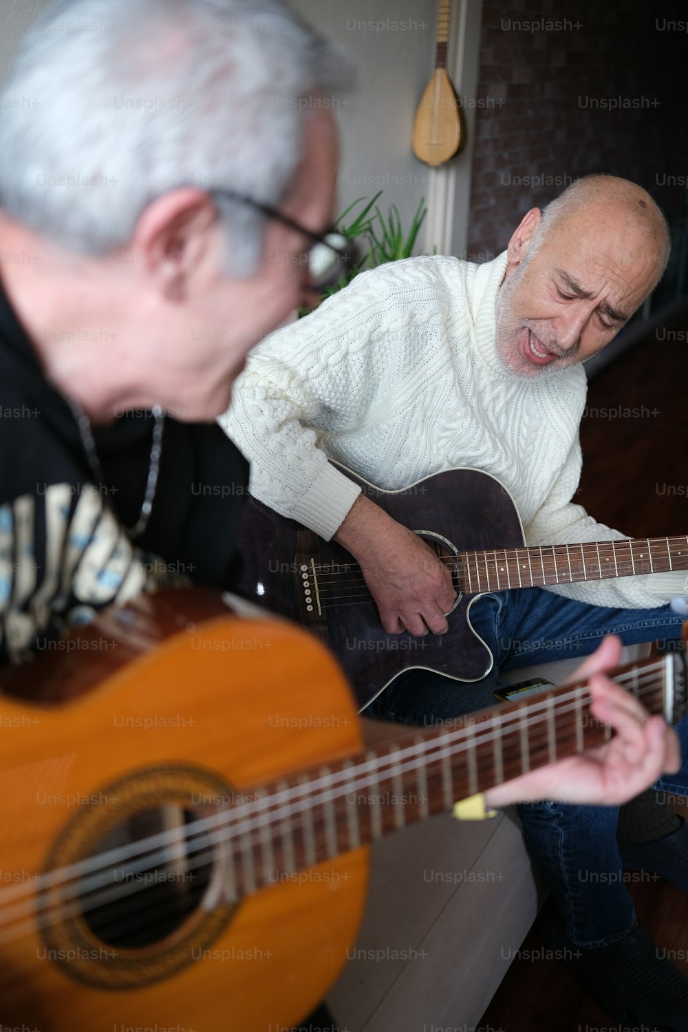 a man playing a guitar next to another man