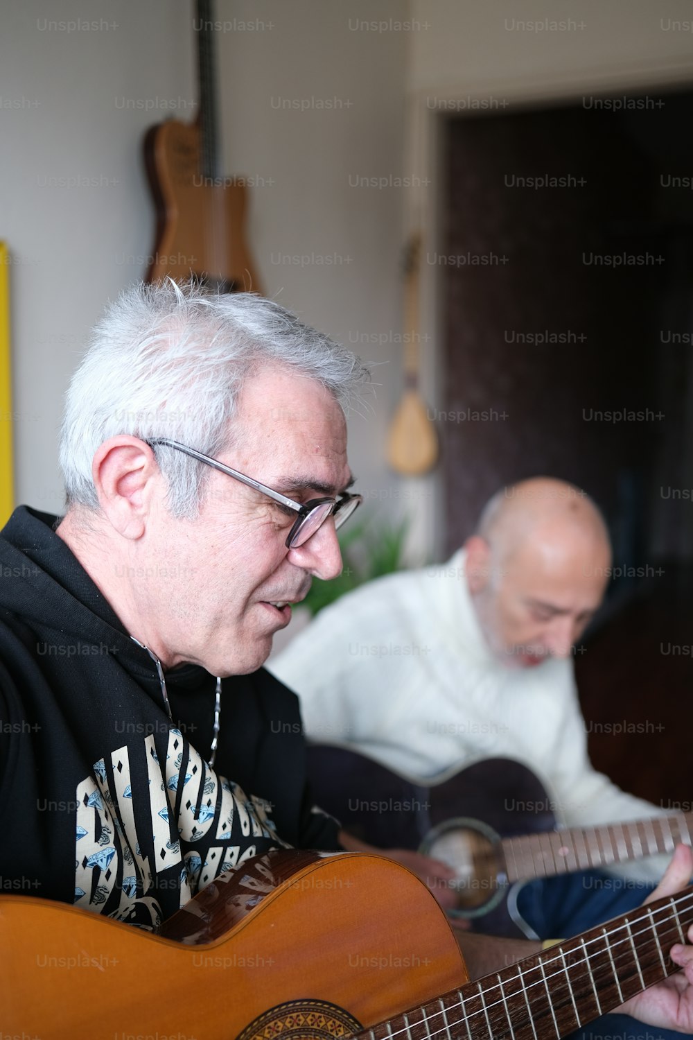 a man playing a guitar while another man plays a guitar