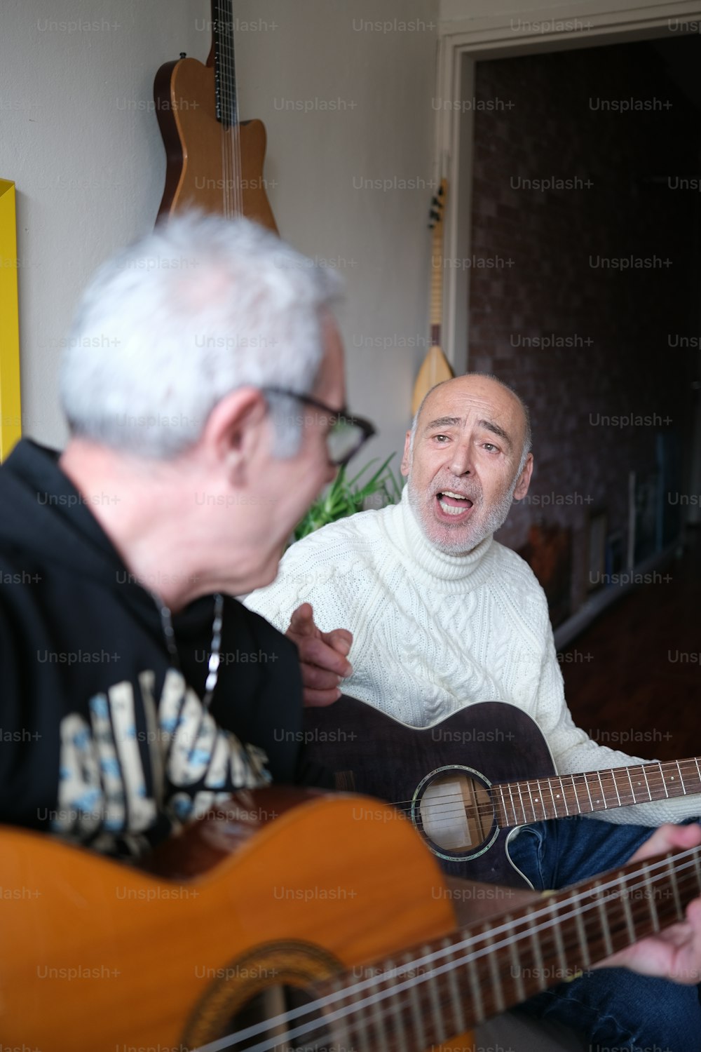 Un hombre tocando una guitarra mientras otro hombre mira
