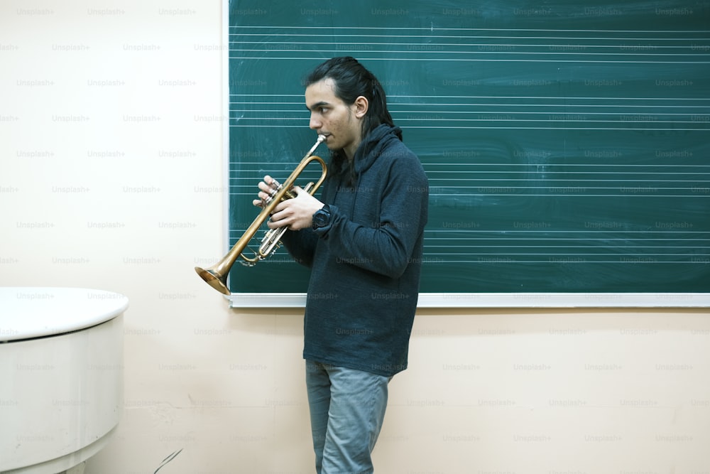 a man playing a trumpet in front of a blackboard