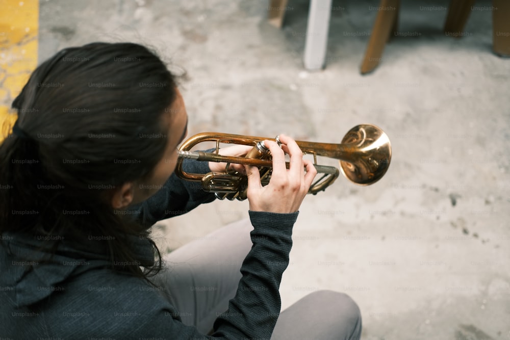 Una mujer tocando una trompeta en el suelo