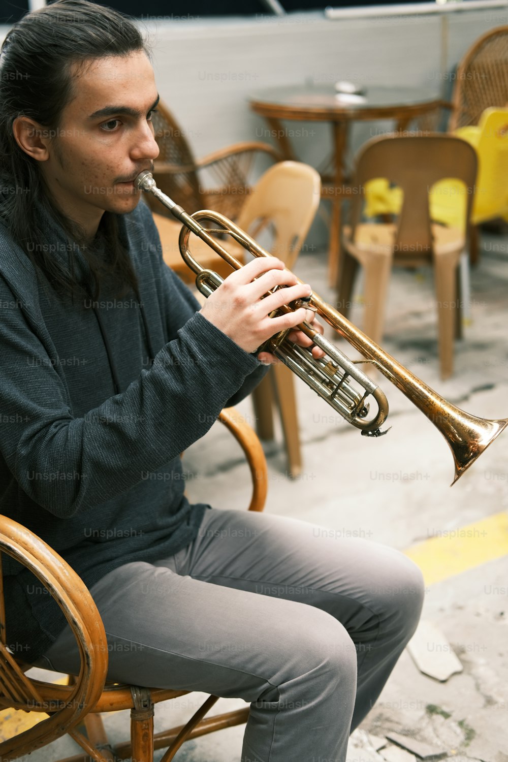 Un hombre sentado en una silla tocando una trompeta