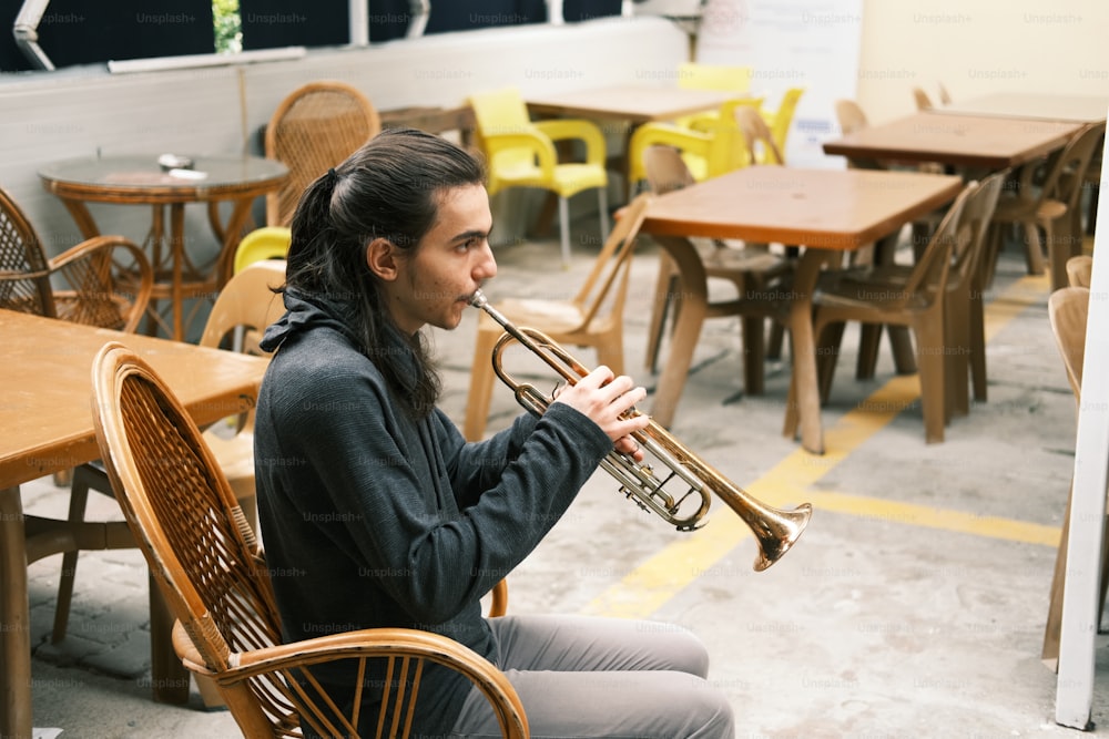 um homem sentado em uma mesa tocando um trompete