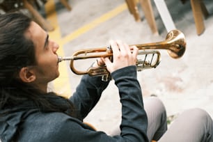 a woman sitting on the ground playing a trumpet