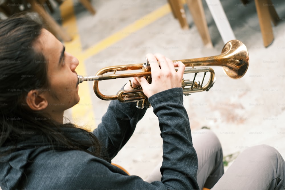 Una mujer sentada en el suelo tocando una trompeta