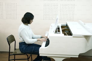 방에서 하얀 피아노 앞에 앉아 있는 여자