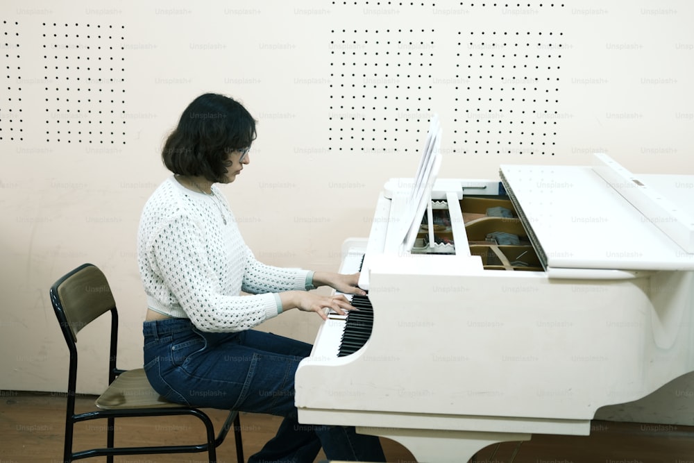 a woman sitting at a white piano in a room