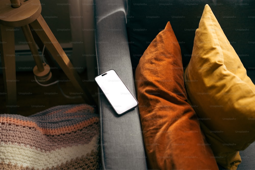 a cell phone sitting on top of a couch next to pillows