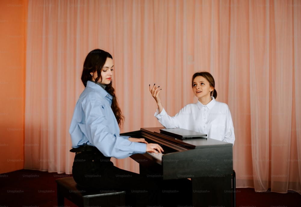 Zwei Frauen, die an einem Klavier sitzen und ein Lied spielen