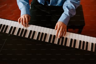 青い�シャツを着た男がピアノを弾いている