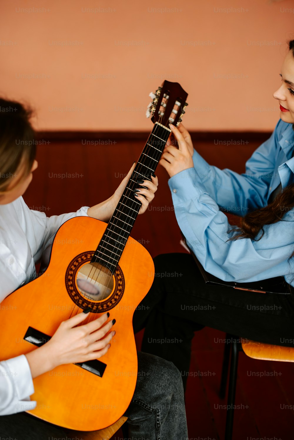 Una mujer sentada junto a una mujer sosteniendo una guitarra