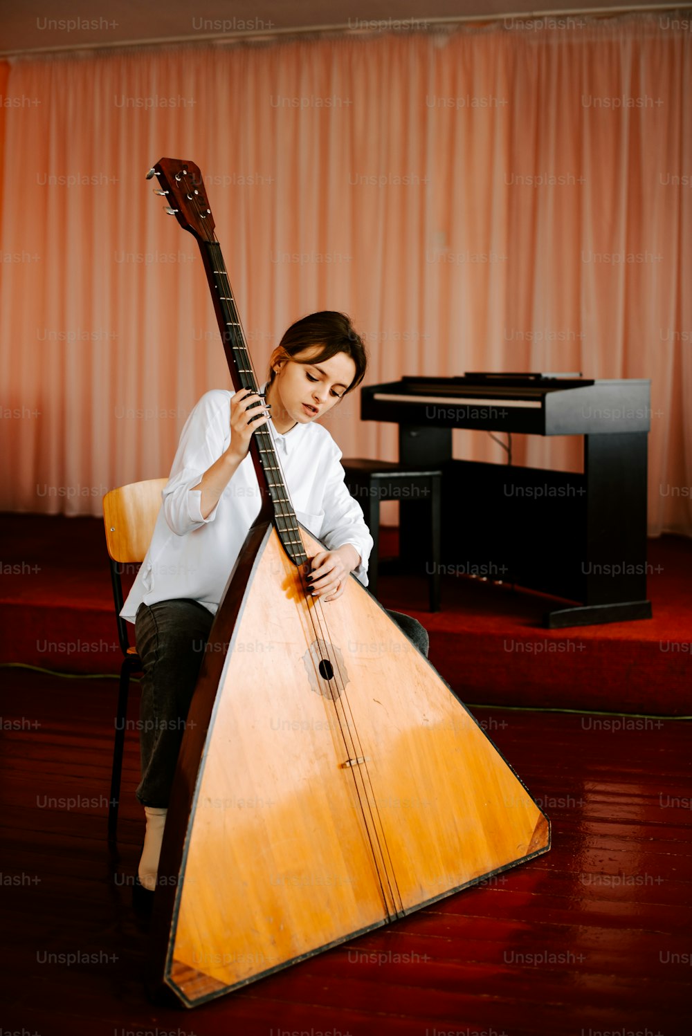 a woman sitting on a chair holding a wooden instrument