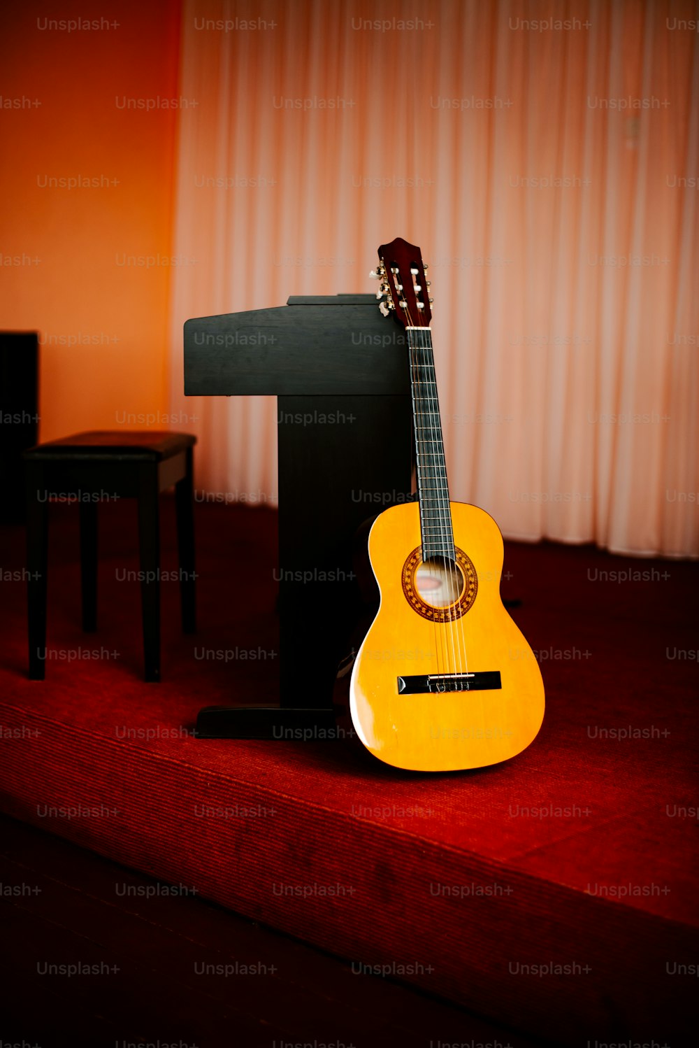 Eine gelbe Gitarre, die auf einem roten Teppich sitzt