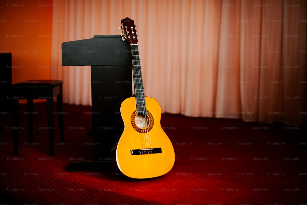 Una chitarra gialla seduta sopra un tappeto rosso