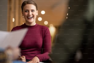 Jeune femme d’affaires riant lors d’une réunion avec des collègues dans un bureau moderne