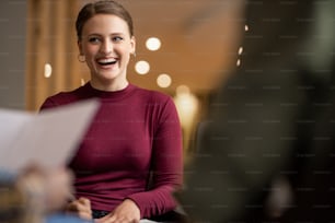 Young businesswoman laughing during a meeting with colleagues in a modern office