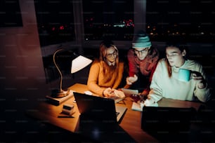 Caucasian male and female students working late at night in office with digital tablet male friend showing information on digital tablet. High quality photo