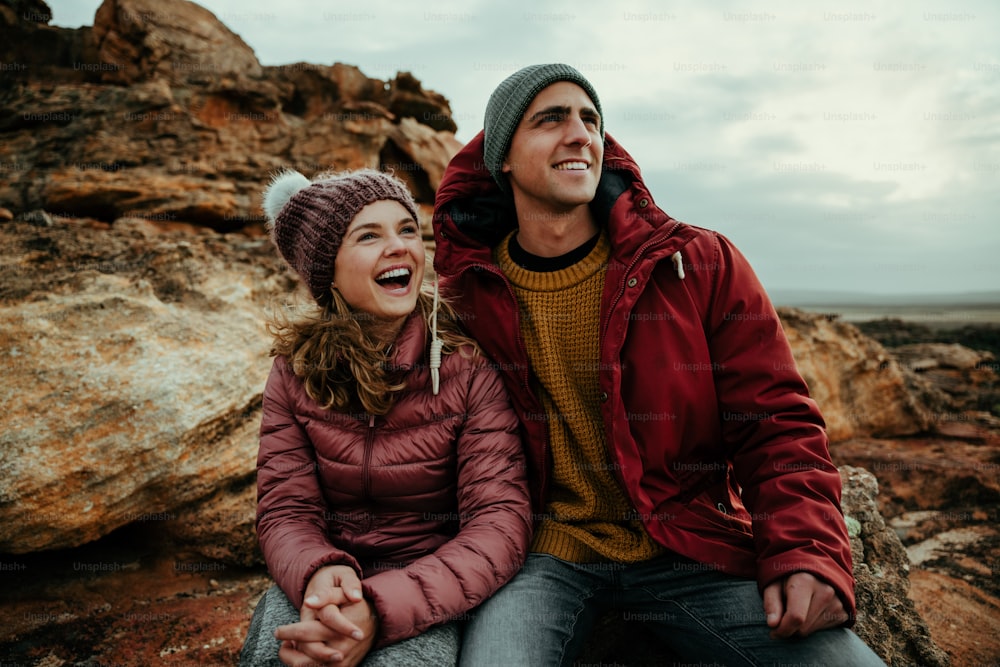 Homme et femme de race blanche riant ensemble assis dans la montagne profitant du plein air et de la nature. Photo de haute qualité