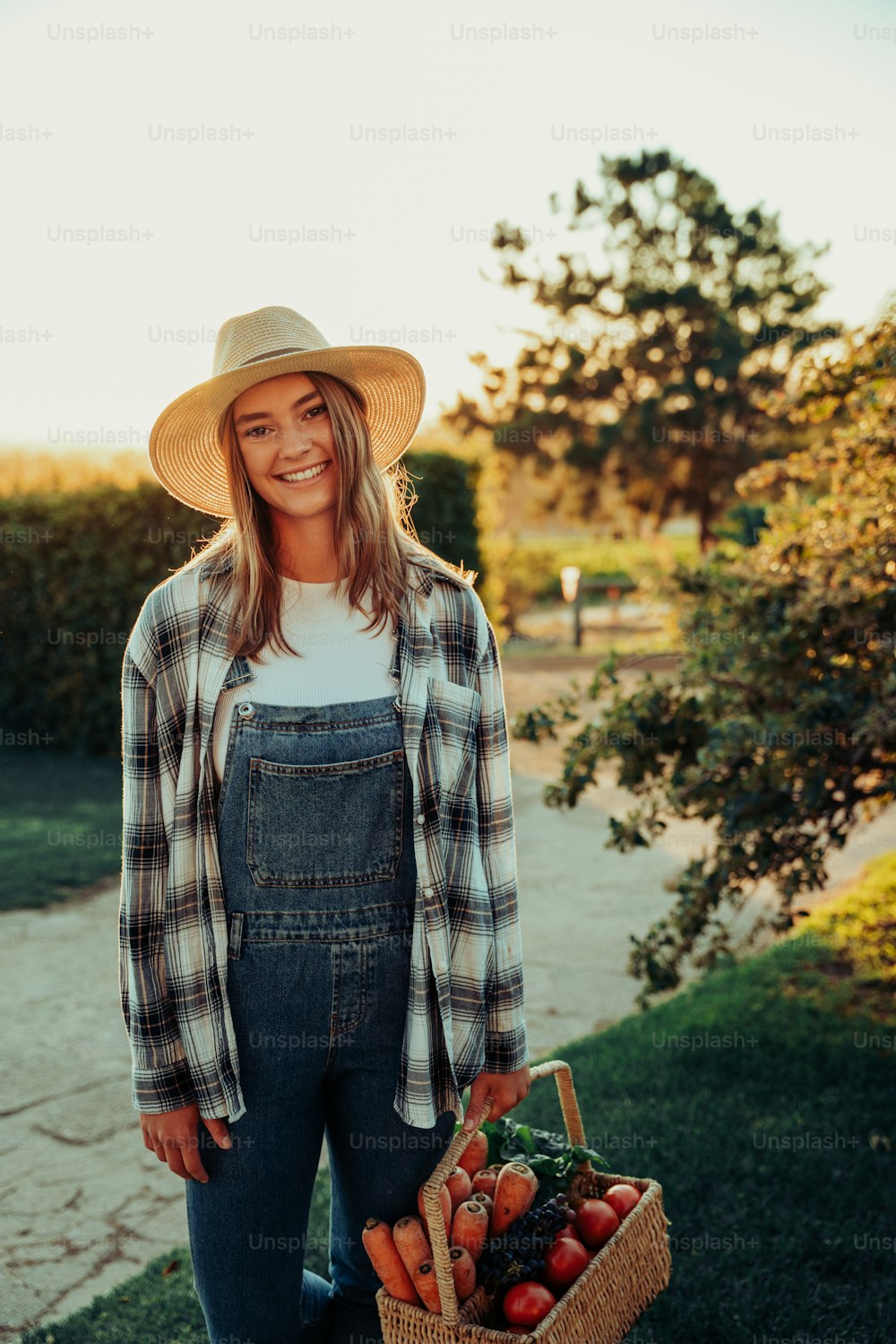 Caucasian female farmer smiling after successfully picking fresh vegetables from garden standing in farmlands at sunrise. High quality photo