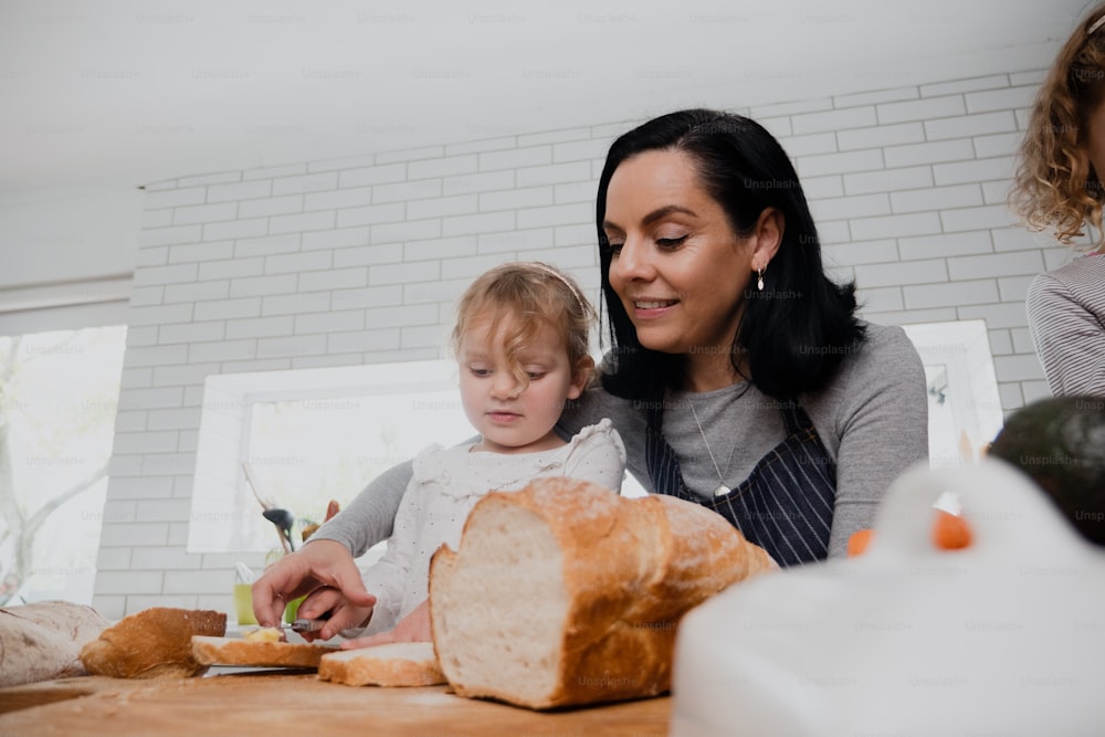 Caucasian mother and daughter cooking in kitchen making lunch for family bonding while slicing bread mkaing sandwiches. High quality photo