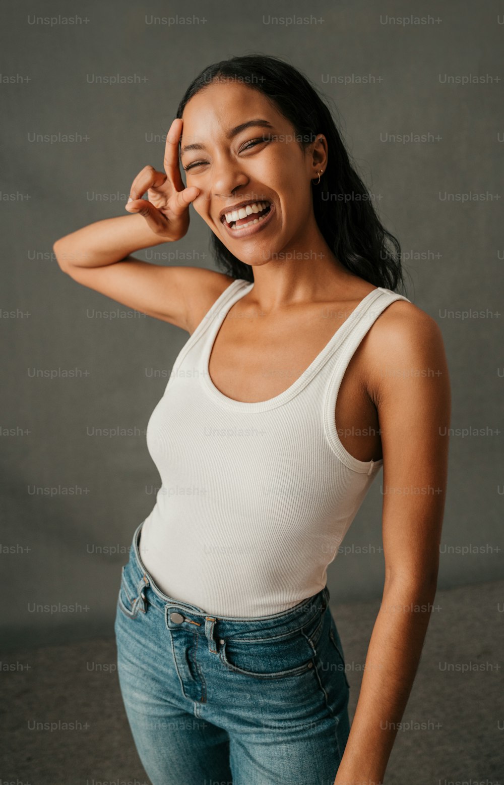 Attractive fun loving African American female standing laughing making a peace sign. High quality photo