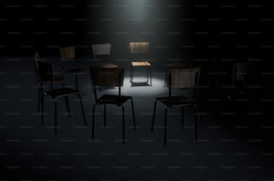 Ein 3D-Rendering-Konzept einer Gruppe von Stühlen in einer kreisförmigen Formation, wobei ein Stuhl durch einen einzigen stimmungsvollen Scheinwerfer auf dunklem Hintergrund hervorgehoben wird