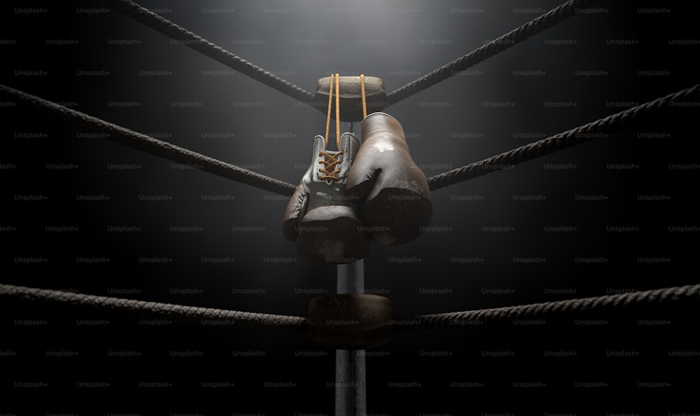 A closeup of the corner of an old vintage boxing ring surrounded by ropes spotlit by a spotlight on an isolated dark background - 3D render