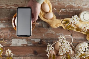 a person holding a cell phone next to some eggs