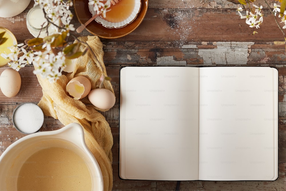 ein offenes Notizbuch neben einer Schüssel mit Eiern und einer Tasse Tee