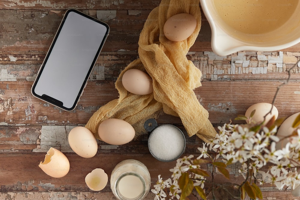 a cell phone sitting on top of a wooden table next to eggs