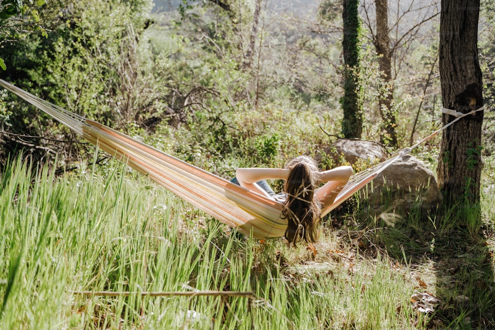 uma mulher deitada em uma rede em uma floresta