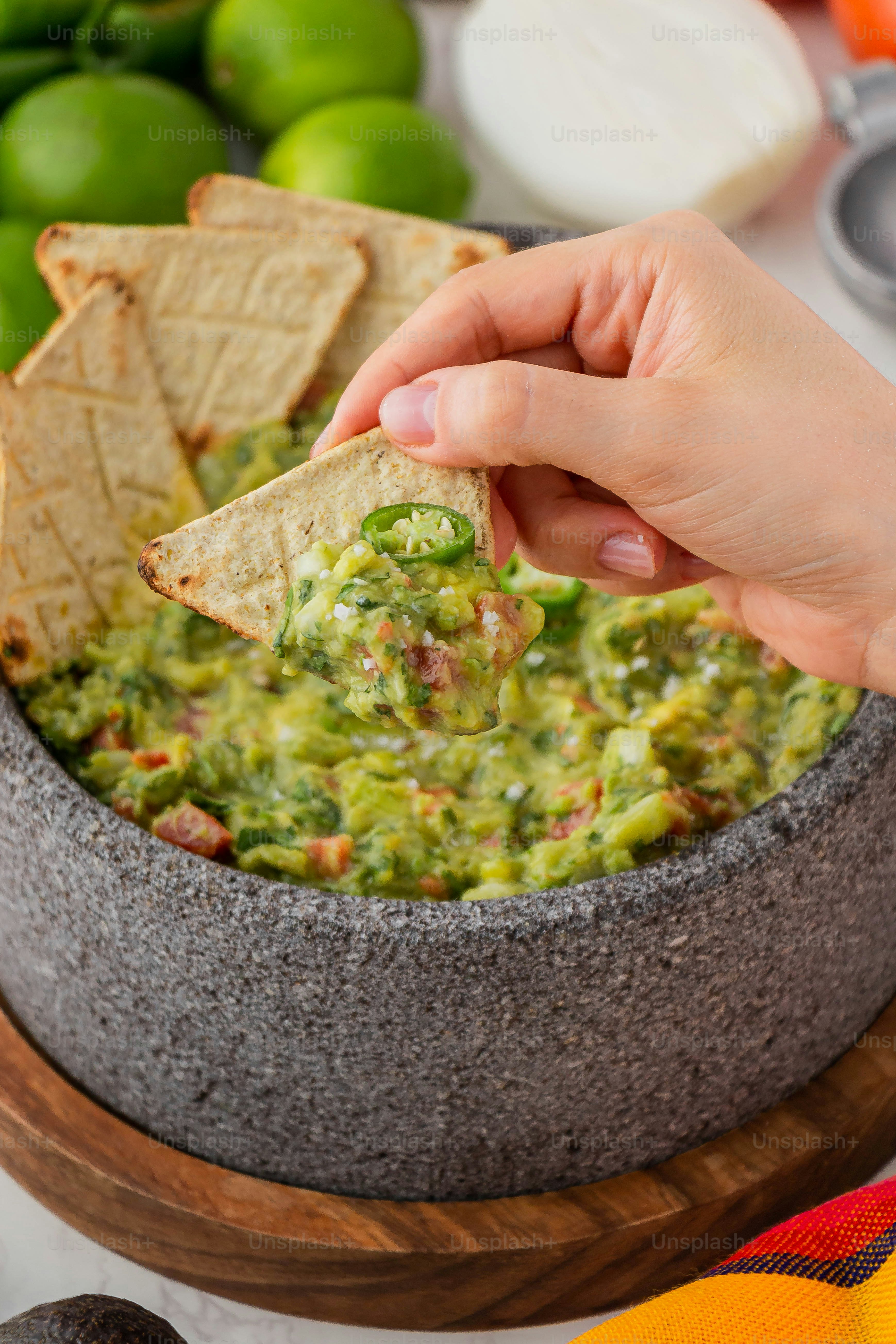 a person dipping a tortilla chip into a bowl of guacamole