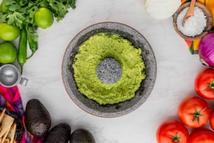 a bowl filled with guacamole surrounded by vegetables