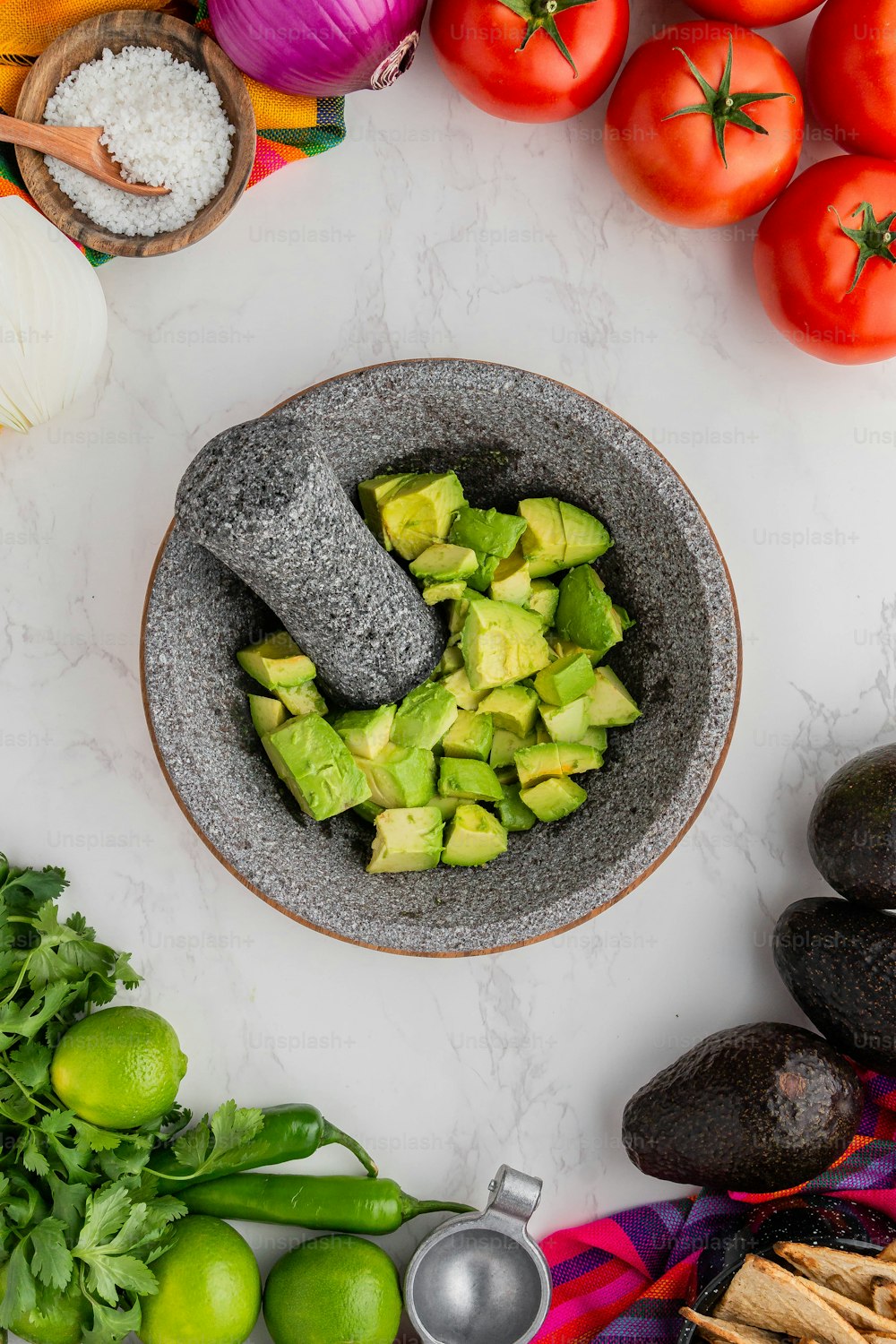 a bowl filled with sliced avocado next to other fruits and vegetables