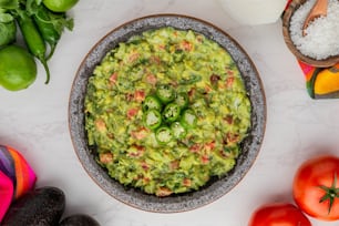 a bowl of guacamole surrounded by vegetables
