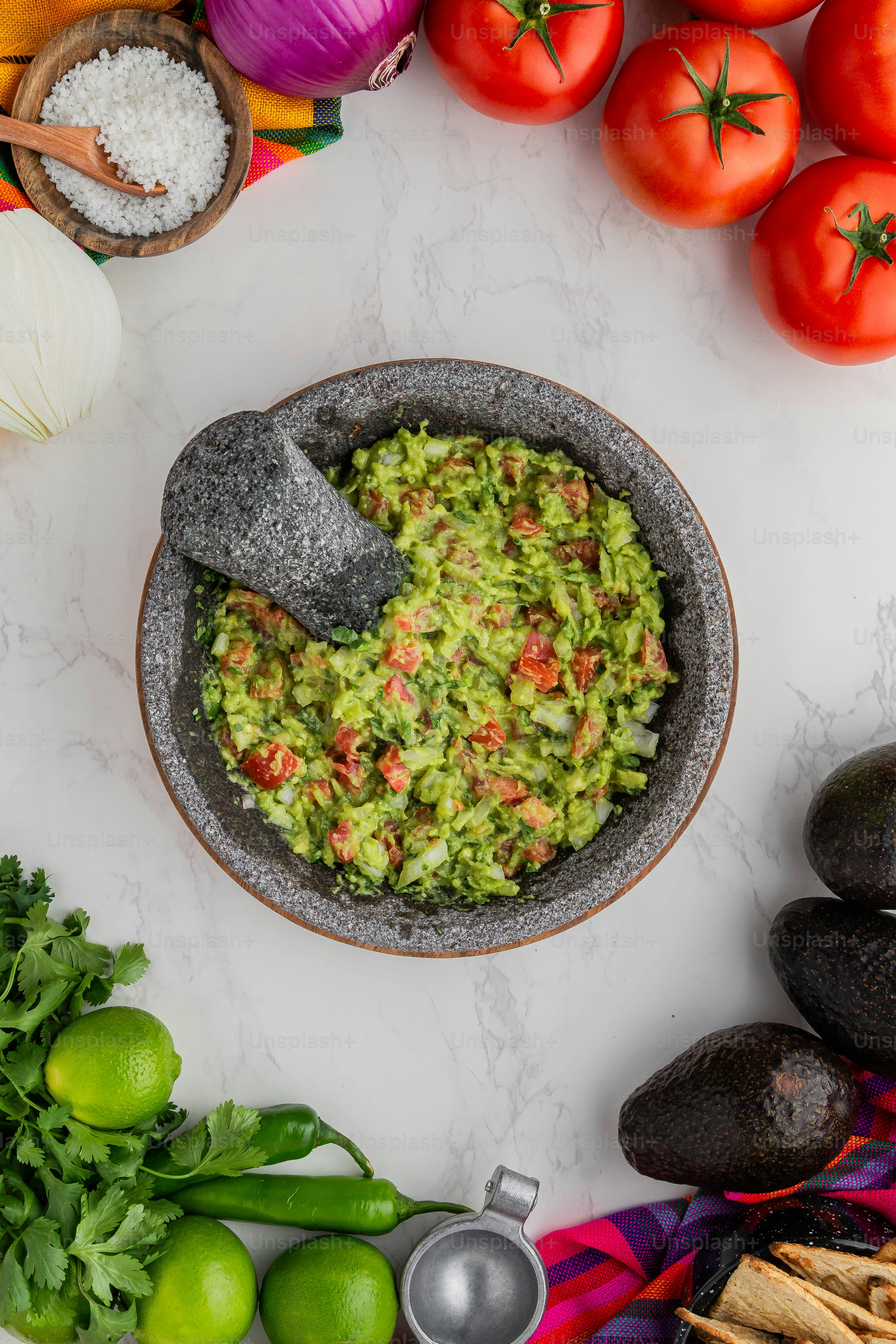 Un tazón de guacamole rodeado de verduras frescas