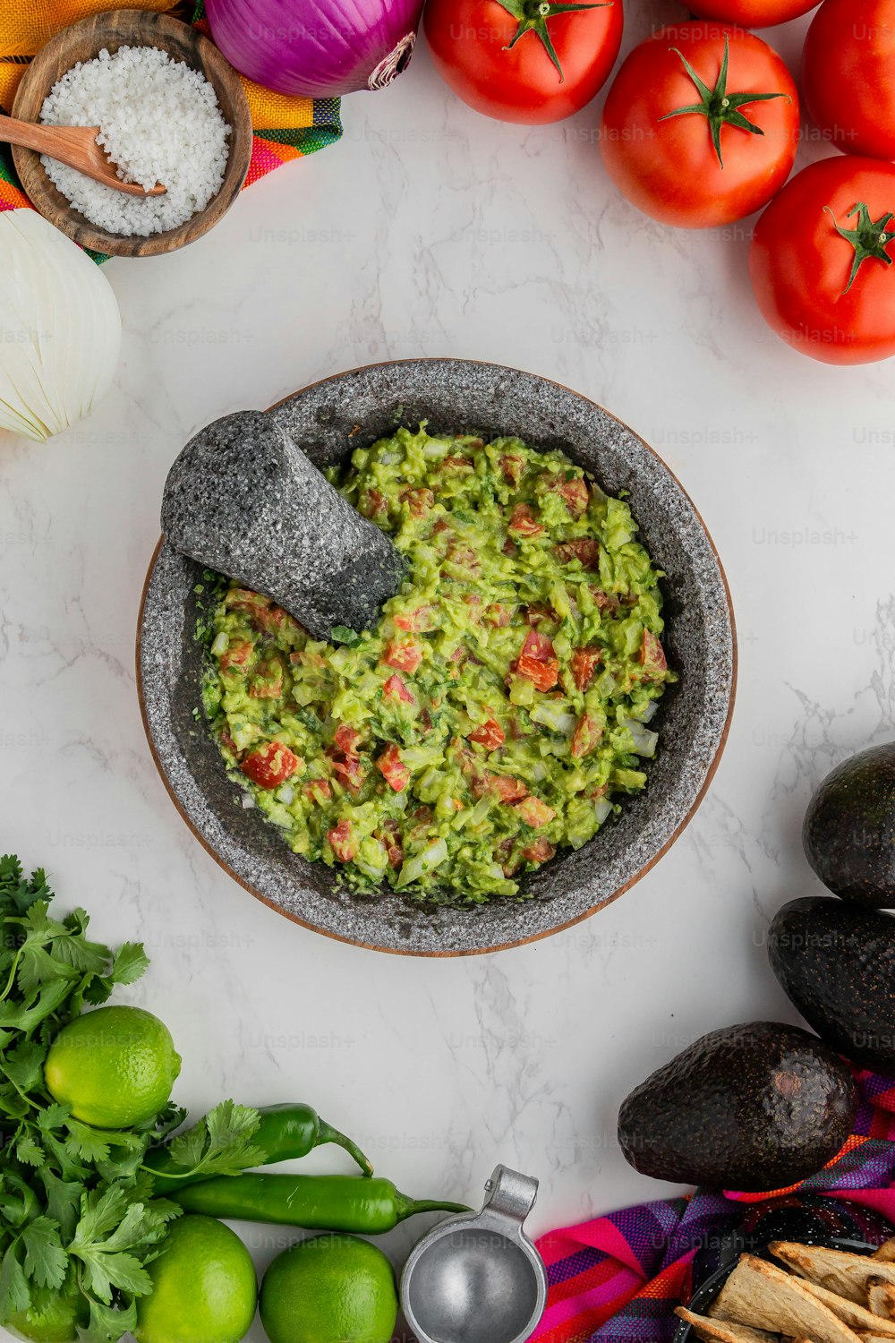 a bowl of guacamole surrounded by fresh vegetables