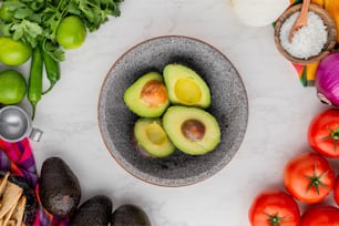 avocados in a bowl surrounded by other vegetables