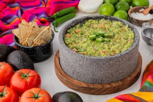 a bowl of guacamole surrounded by fresh fruit and vegetables