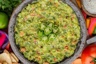 a bowl of guacamole surrounded by chips and vegetables