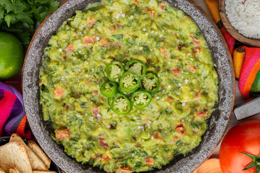 a bowl of guacamole surrounded by chips and vegetables