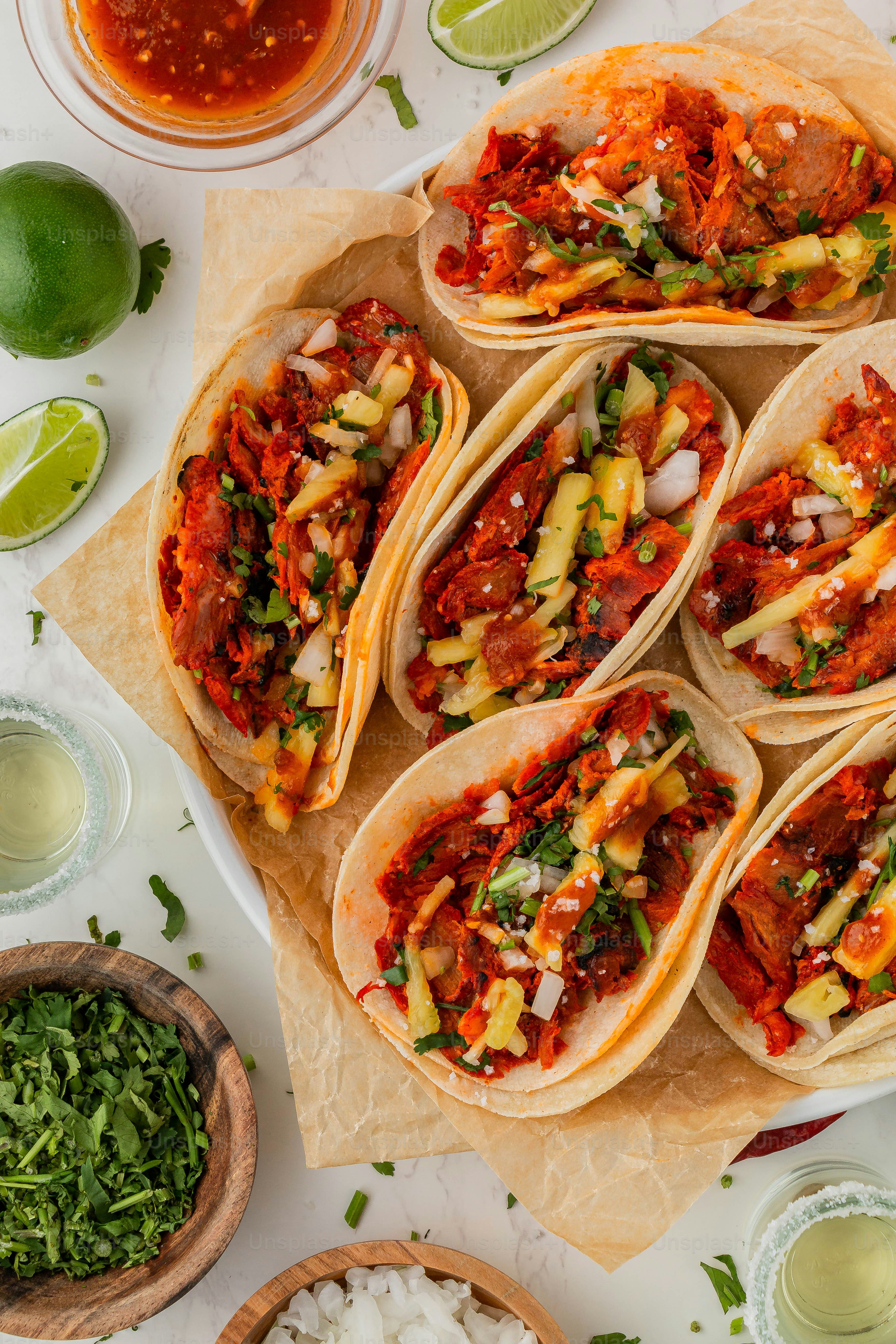 a table topped with lots of tacos covered in sauce