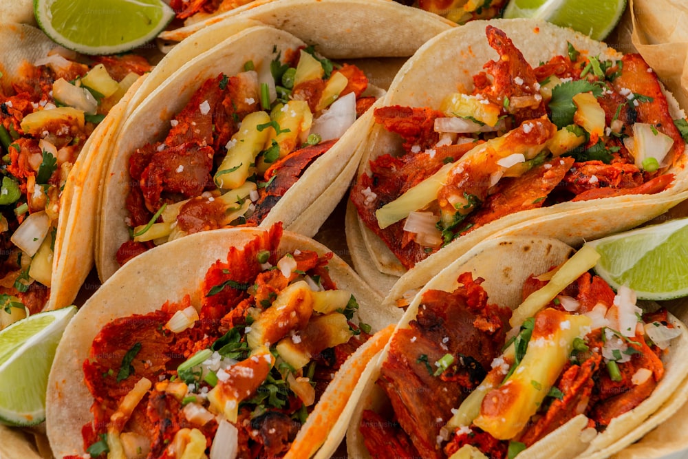 Une assiette pleine de tacos et de quartiers de citron vert