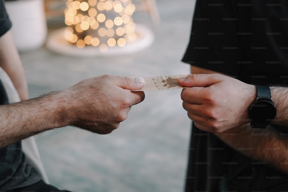 two men exchanging a piece of paper with a christmas tree in the background