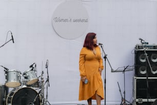 Una mujer con un vestido amarillo parada frente a un micrófono