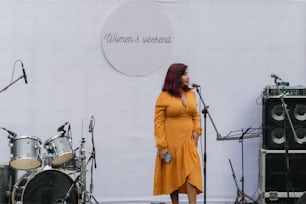 a woman in a yellow dress standing in front of a microphone