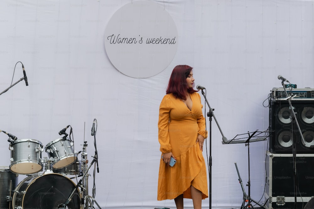 a woman in a yellow dress standing in front of a microphone