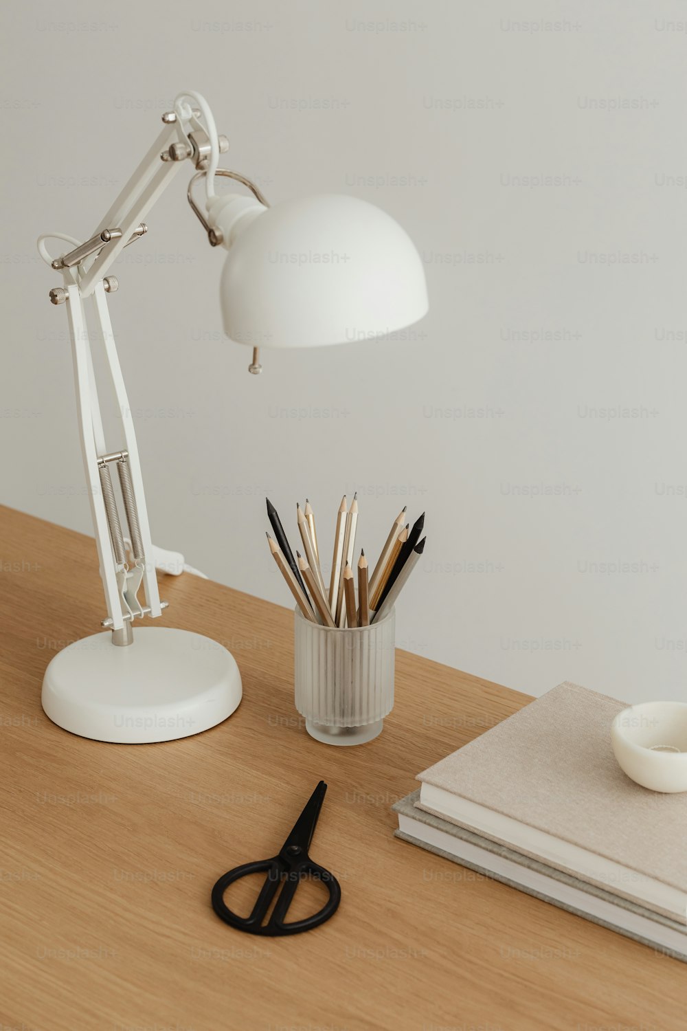 a desk with a lamp, pencils and a cup on it